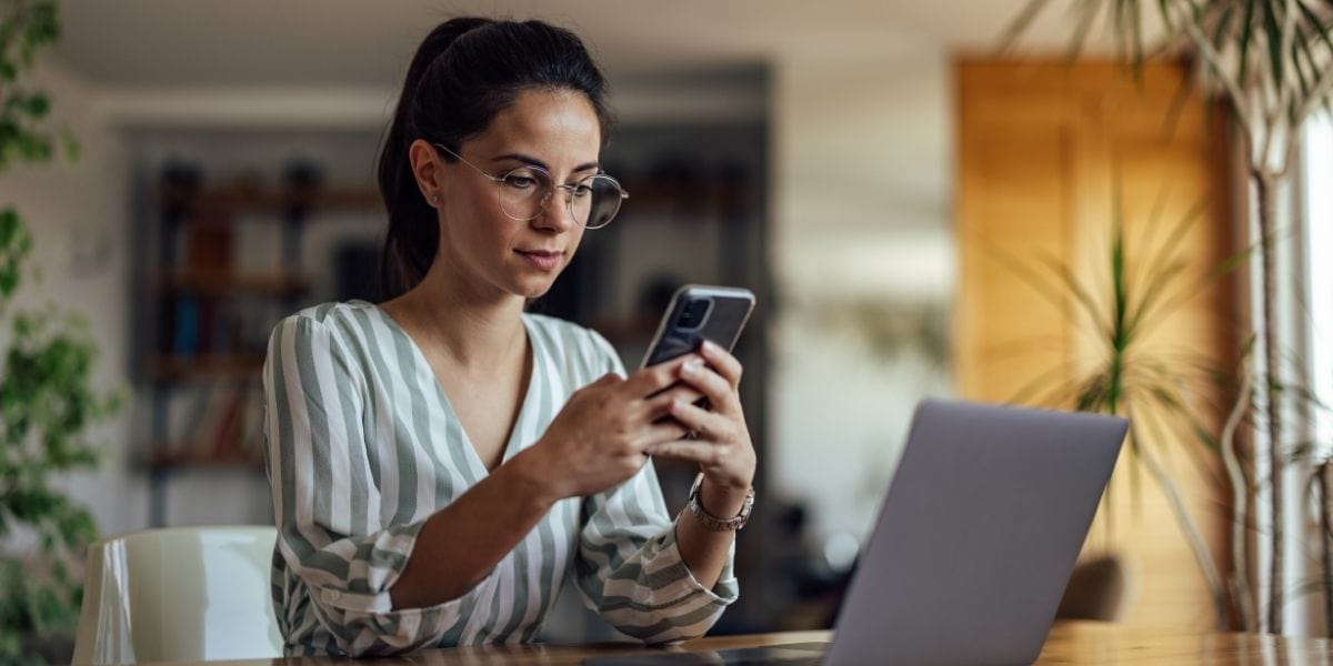 Website für VA-Business und Virtuelle Assistenz, Frau am Laptop mit Handy in der Hand