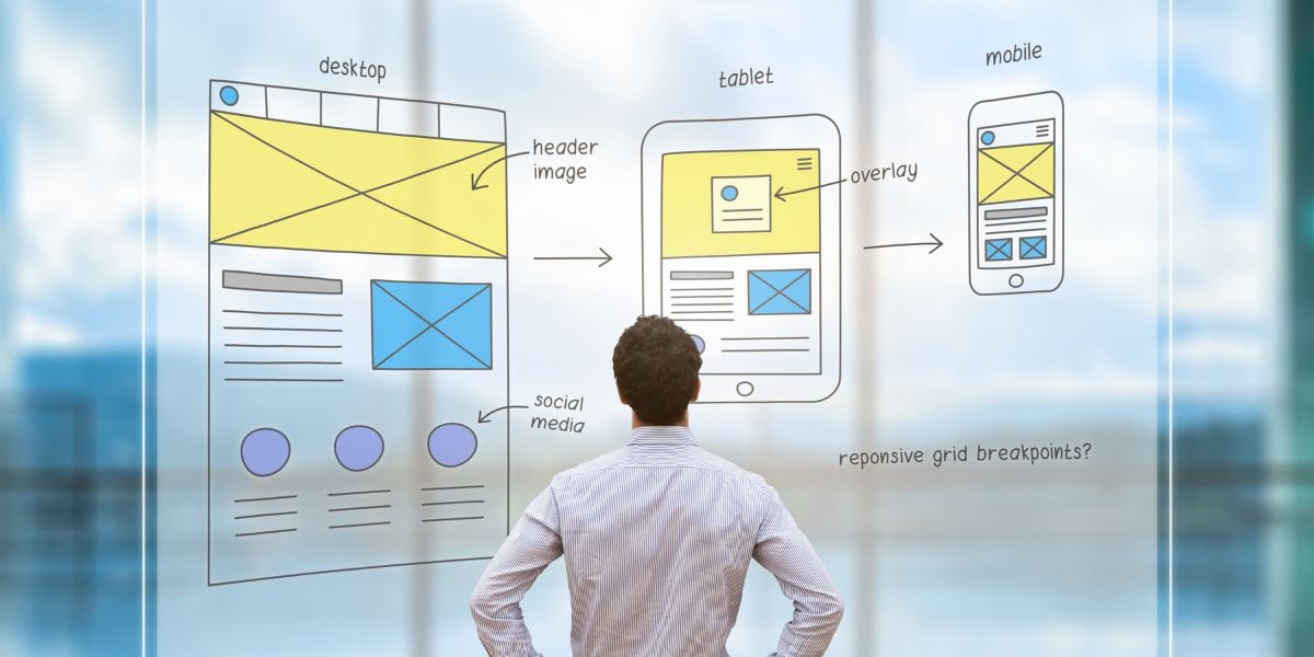Erstellung neue Website, hier Mann, der vor eines Glaswand mit Website Mockups steht