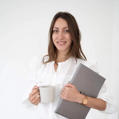 Im Bild Teammitglied Vanessa Strasser, E-Mail-Marketing-Managerin, mit Kaffeetasse in der Hand und Laptop unter dem Arm