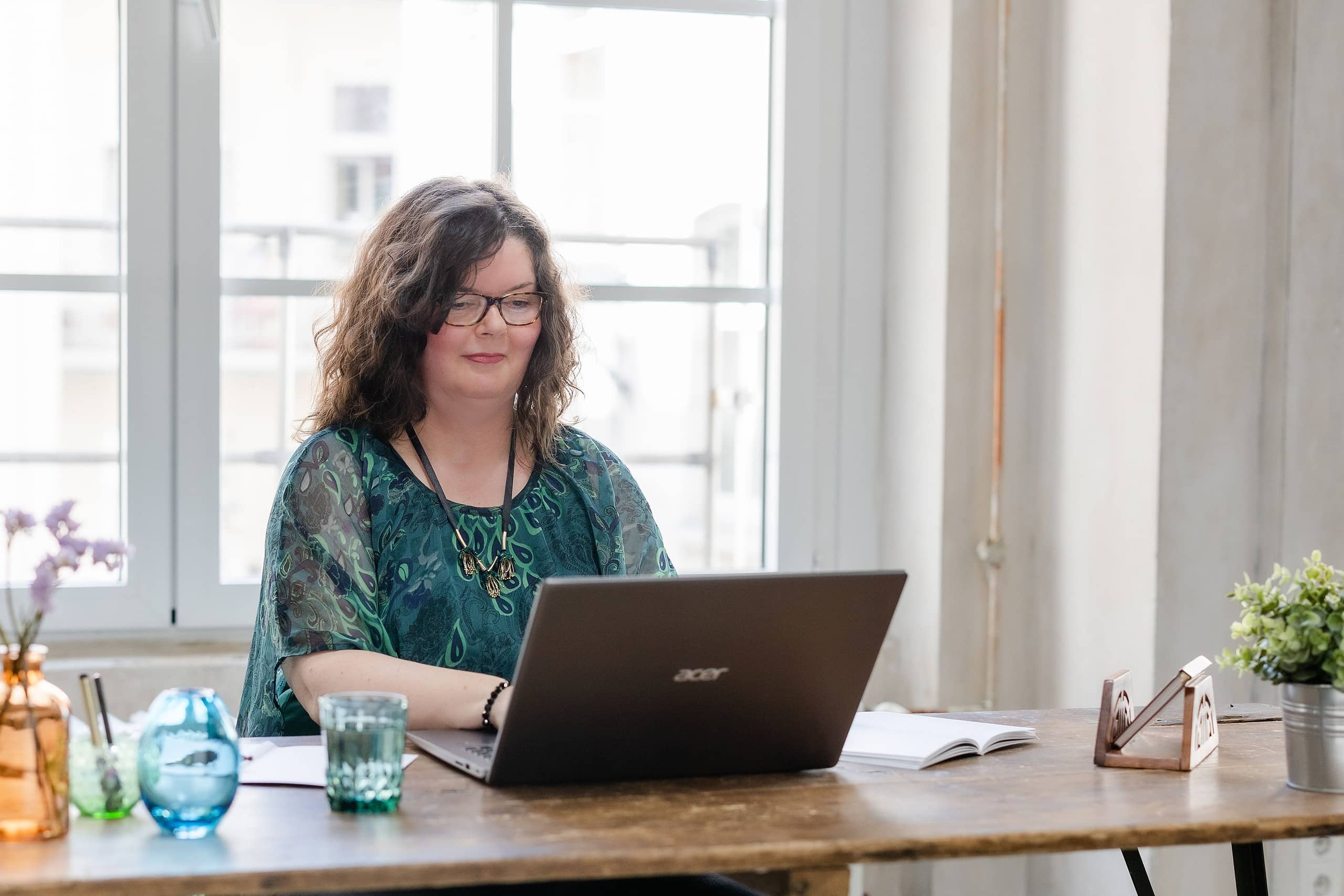 Maria Squarra, hier am Schreibtisch mit Laptop und Wasserglas aus grünem Glas